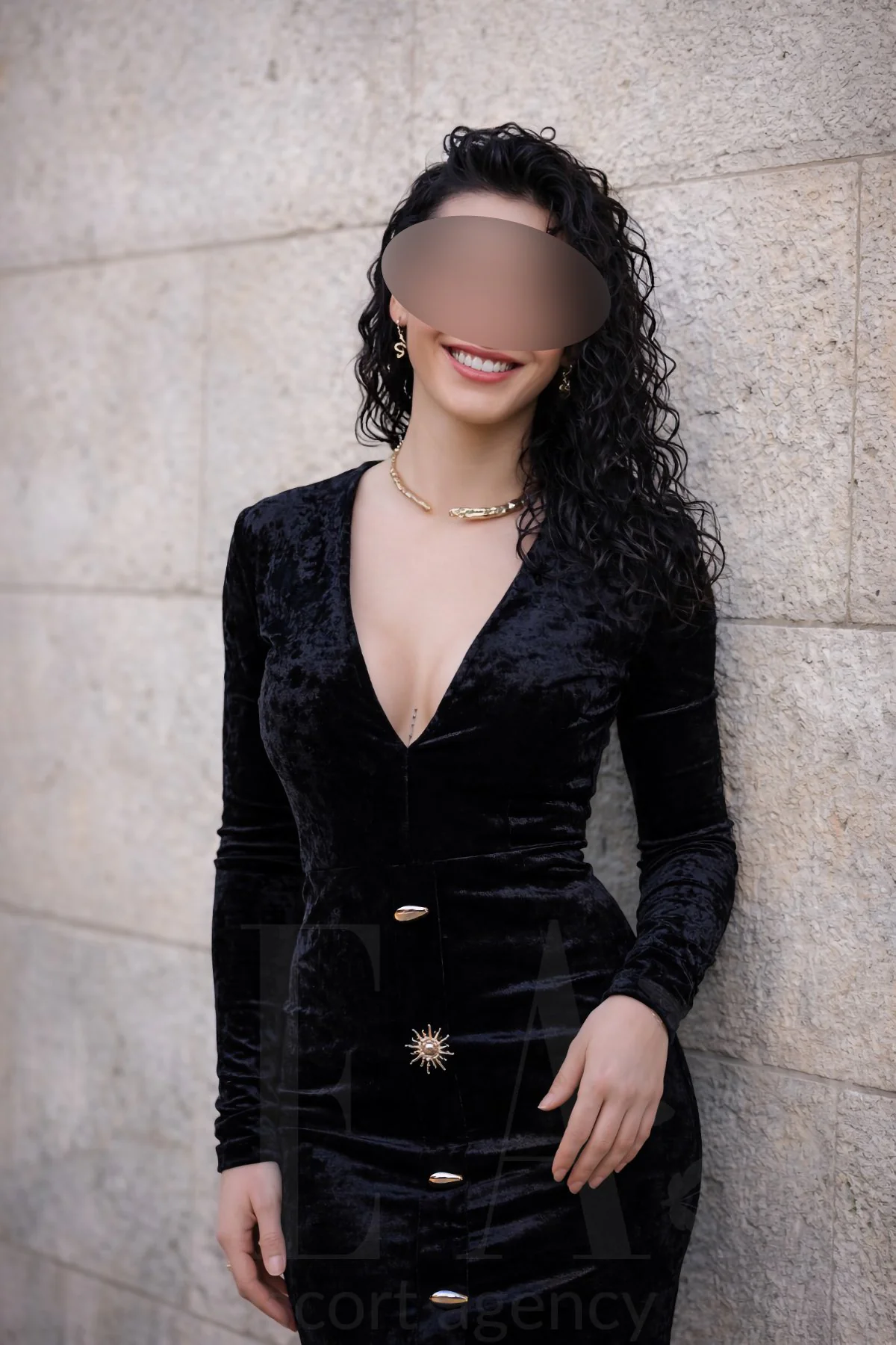 Escort Nora im schwarzen Samtkleid an der Mauer in München