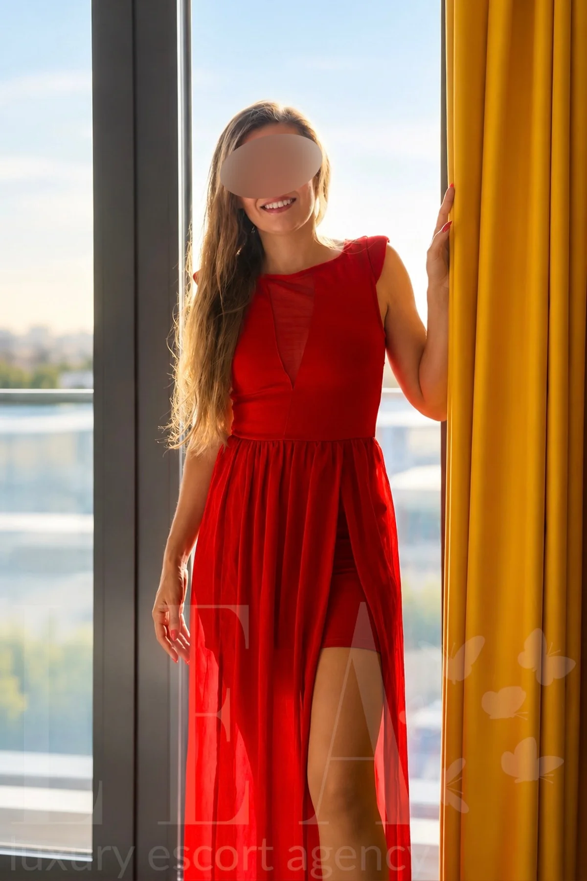 Luxus Escort Leto in Heidelberg im roten Abendkleid am Fenster