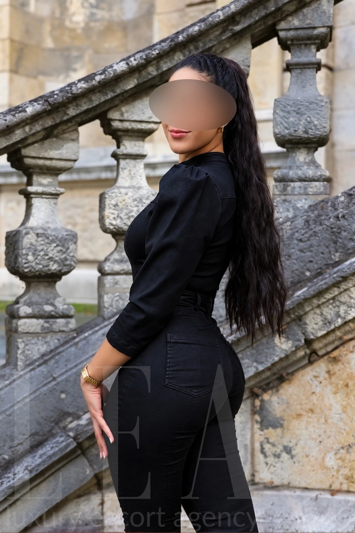 Escort Girl Stella aus München im schwarzen Lederoverall auf der Treppe